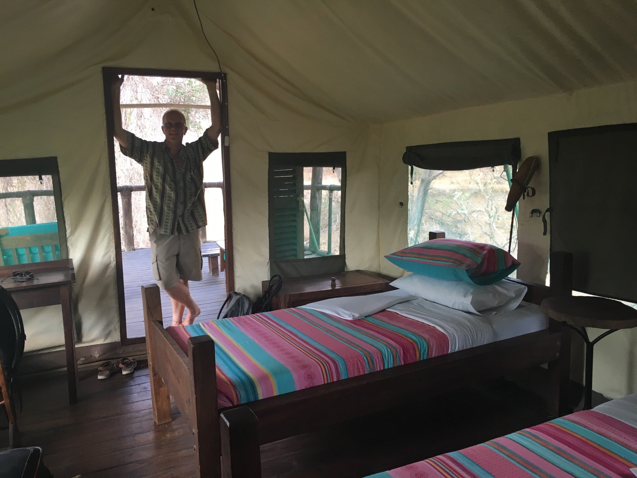 A man standing in the doorway of a twin-bedded safari tent in Ruaha