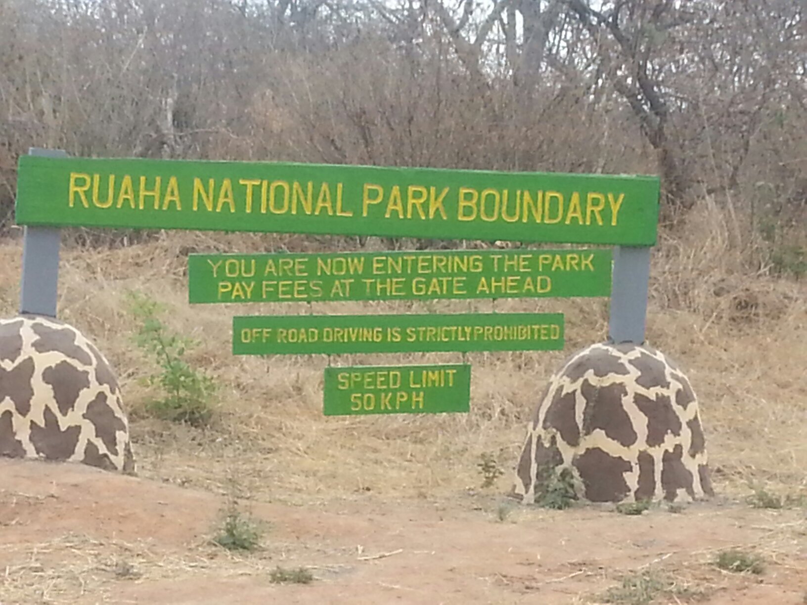 A painted national park boundary sign set among whitewashed rocks at the edge of the bush